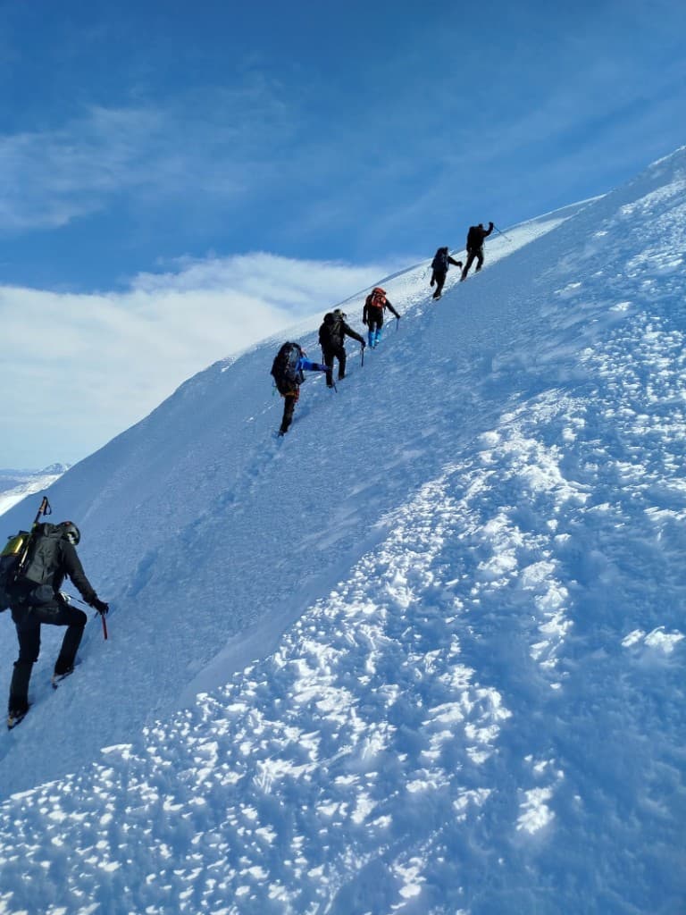 Montañistas ascendiendo en terreno nevado