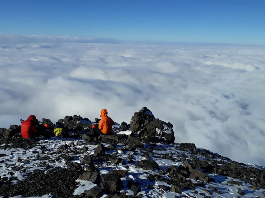 Montañistas en la cumbre sobre un mar de nubes